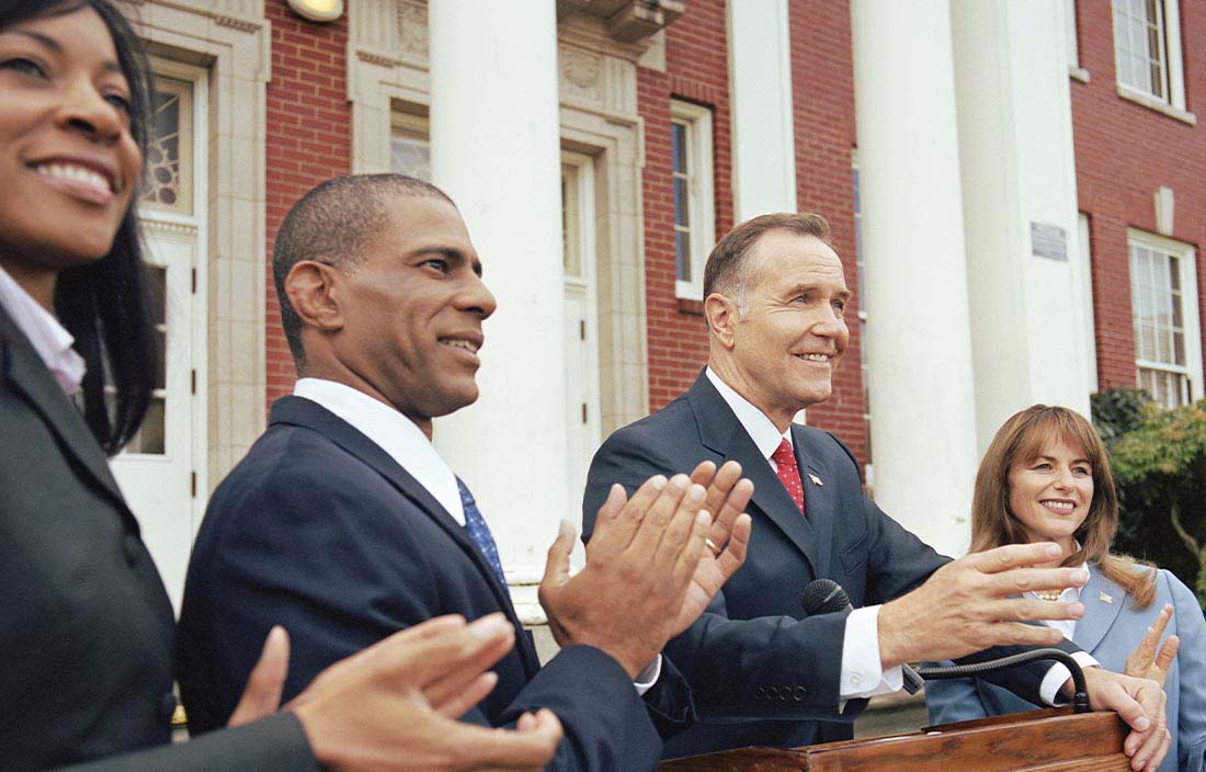 Group of business professionals clapping outside of a historic building.